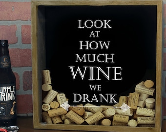 May include: A wooden shadow box with a black background and the text "LOOK AT HOW MUCH WINE WE DRANK". The box is filled with wine corks.
