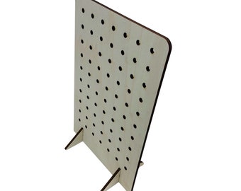 May include: A wooden pegboard with a stand, featuring a grid of evenly spaced holes. The pegboard is light brown with a natural wood grain.