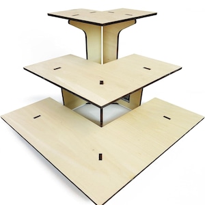 May include: A three-tiered, L-shaped display stand made of light-colored wood. Each tier is a different size, with the top tier being the smallest. The edges are dark brown. The stand is designed to showcase products.