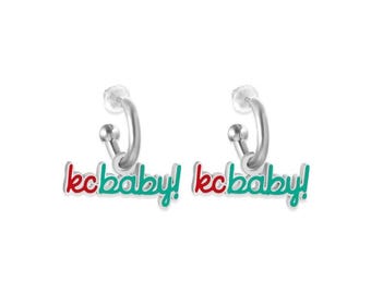 Może przedstawiać: Para srebrnych kolczyków koła z napisem "kcbaby!" wykonanym w czerwonej i zielonej emalii.