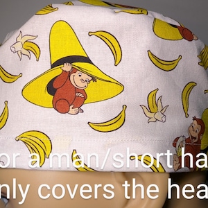 May include: White fabric scrub hat with a yellow banana print and a cartoon monkey wearing a yellow hat. The text "For a man/short hair (only covers the head)" is printed on the bottom of the hat.