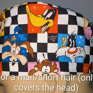 May include: A colorful head covering featuring cartoon characters like Daffy Duck, Sylvester, and Wile E. Coyote. The design includes a checkerboard pattern and various cartoon panels. The text on the image says "For a man/short hair (only covers the head)".