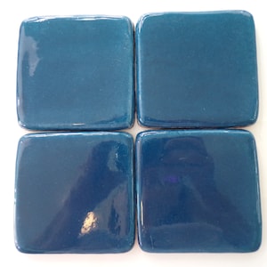 May include: Four square teal ceramic tiles arranged in a grid pattern.