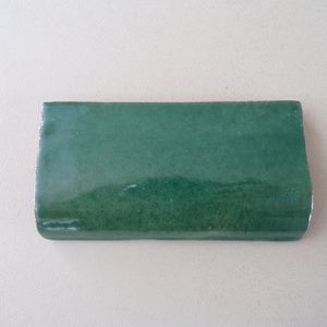 May include: A single green ceramic tile with a smooth, glossy finish.