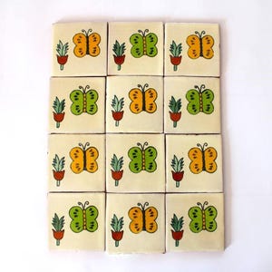 May include: A set of 12 ceramic tiles with a repeating pattern of green and yellow butterflies with red and green floral accents.