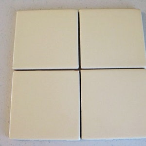 May include: Four off-white square ceramic tiles arranged in a 2x2 grid.