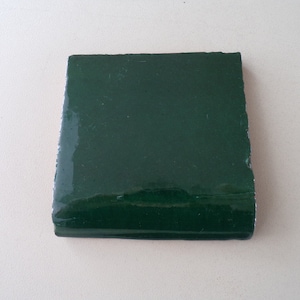 May include: A dark green ceramic tile with a glossy finish.