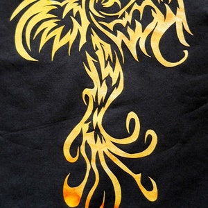 May include: A gold tribal phoenix design on a black background. The phoenix is depicted with its wings spread and its tail feathers flowing.