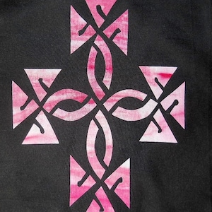 Könnte beinhalten: Ein pinkfarbenes keltisches Knotendesign auf einem schwarzen Stoffhintergrund. Der Knoten hat die Form eines Kreuzes.