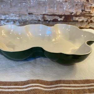 May include: A shallow, multi-lobed serving dish with a glossy dark forest green exterior and a smooth, cream-colored interior. The bowl features a distinct, organic, cloud-like shape with curved, scalloped edges and a wide, open basin design.