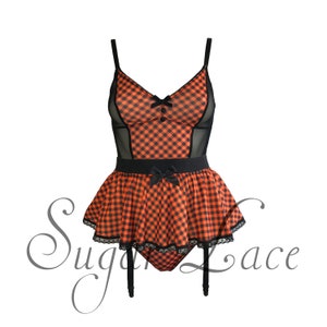 May include: A bodysuit featuring an orange and black gingham pattern with black mesh side panels, thin shoulder straps, two small buttons, and a ruffled skirted waist. The garment includes black bows and lace trim, with the text Sugar Lace overlaid.