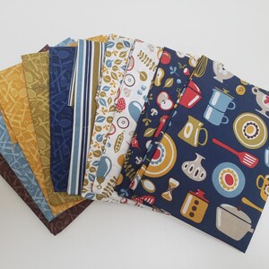 May include: A set of 10 fabric squares featuring various kitchen-themed patterns in shades of blue, yellow, and brown. The patterns include kitchen utensils, food, and dishes.