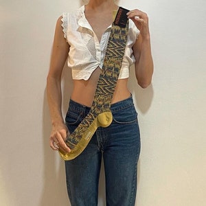 Könnte beinhalten: Eine Person trägt ein weißes Crop-Top mit Spitzenmuster und blaue Jeans. Sie hält eine lange, gemusterte Socke mit dem Aufdruck "Mossimo" in der Hand.