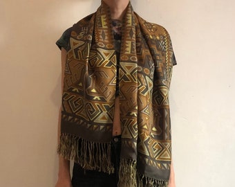 May include: A brown and gold patterned silk scarf with fringe. The scarf has a geometric design with brown, gold, and white accents.
