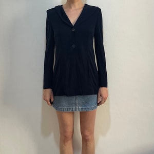 Può includere: Una giacca blu navy a maniche lunghe, scollo a V e chiusura con un bottone.