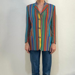 May include: A colorful striped blazer with a yellow button closure. The blazer is made of a lightweight fabric and has a relaxed fit.