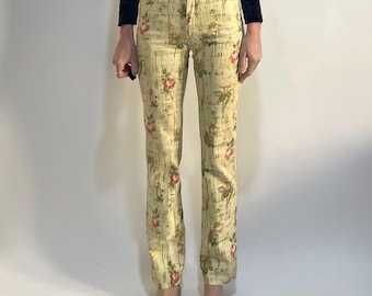 May include: A black velvet wrap top with long sleeves and a tie closure, paired with light yellow floral print jeans. The jeans feature a pattern of red roses and green leaves.