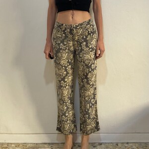 May include: A black sleeveless crop top with a lace-up detail at the front, paired with grey floral print trousers.