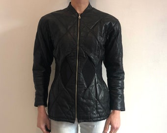 May include: A black quilted leather jacket with a zipper closure and a diamond pattern. The jacket has a fitted waist and long sleeves.