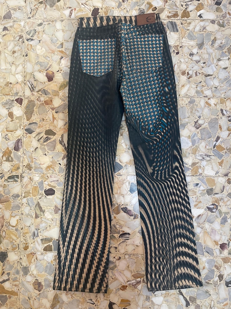 Puede incluir: Vaqueros de rayas blancas y negras con un patr&oacute;n de pata de gallo azul y blanco en los bolsillos traseros.