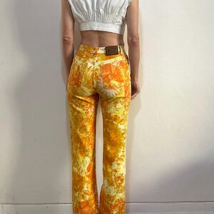 May include: A pair of yellow and orange tie-dye flared jeans with a brown leather patch on the back.