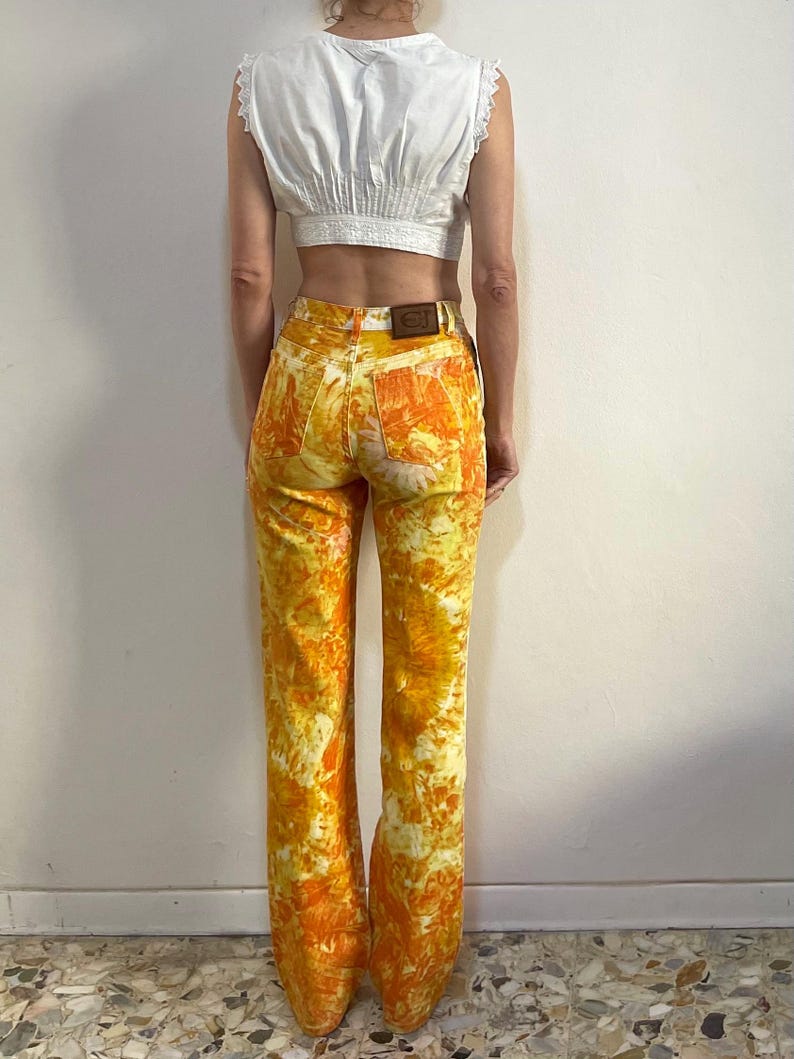 May include: A pair of yellow and orange tie-dye flared jeans with a brown leather patch on the back.