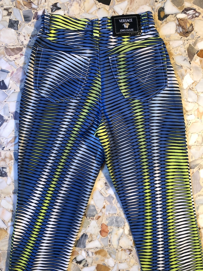Puede incluir: Vaqueros con estampado azul, amarillo y blanco con una etiqueta negra de Versace Jeans Couture en la parte posterior.