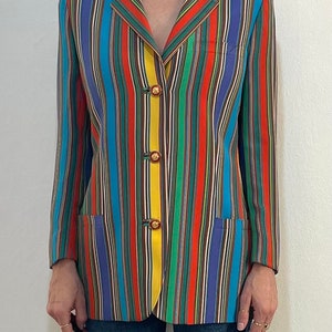 May include: A multi-colored striped blazer with a yellow stripe down the front. The blazer has four gold buttons.