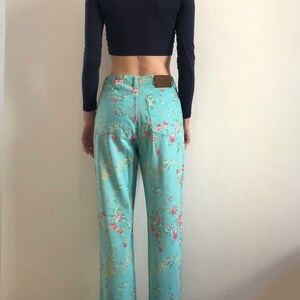 May include: A pair of light blue jeans with a floral print. The jeans have a straight leg and a high waist.