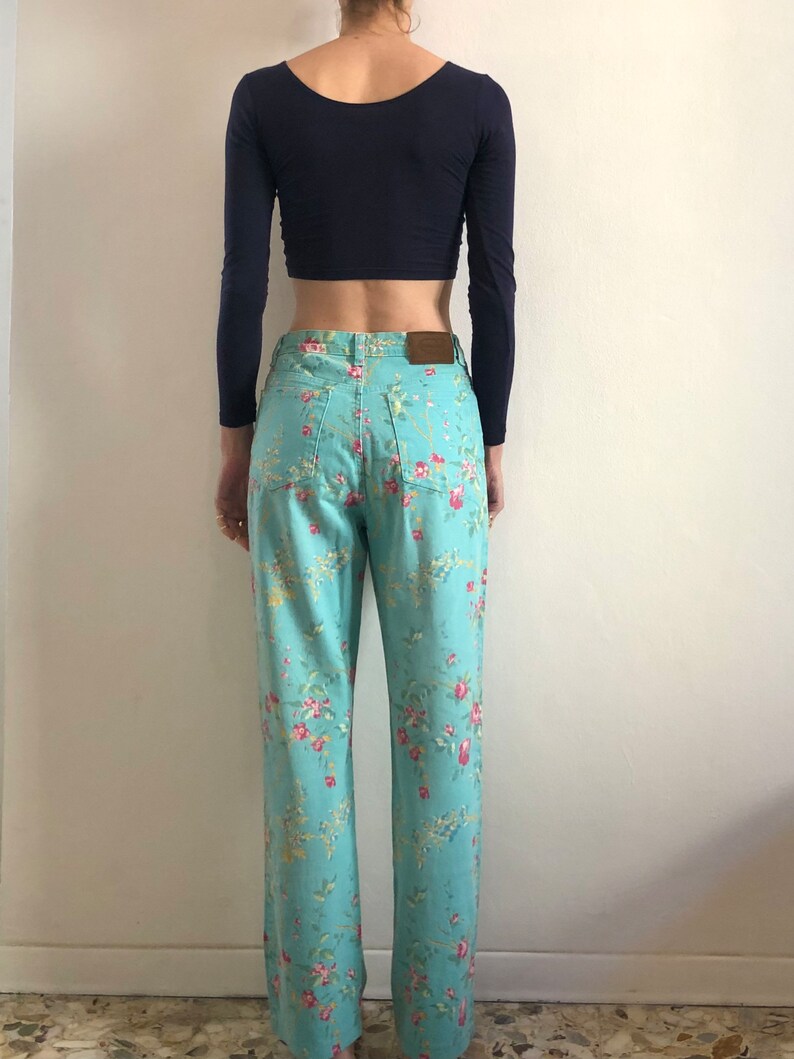 May include: A pair of light blue jeans with a floral print. The jeans have a straight leg and a high waist.