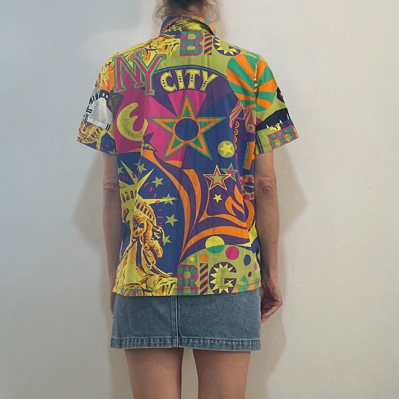 K&ouml;nnte beinhalten: Ein farbenfrohes Hemd mit Kn&ouml;pfen und einem psychedelischen Muster mit einem Stern, der Freiheitsstatue und dem Text "NY CITY".