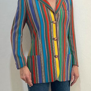 May include: A colorful striped blazer with a yellow stripe down the front and gold buttons. The blazer is made of a smooth fabric and has a classic cut.