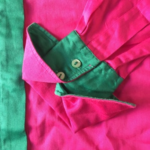 Puede incluir: Primer plano de una camisa rosa y verde con un pu&ntilde;o abotonado. La camisa est&aacute; hecha de una tela suave y sedosa.