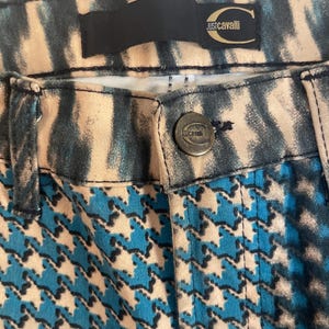 Puede incluir: Pantalones de patr&oacute;n azul y blanco con una cintura de estampado de cebra en blanco y negro. Los pantalones tienen un bot&oacute;n de metal dorado con el texto "Just Cavalli" en &eacute;l.