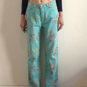 May include: A pair of light blue jeans with a floral print. The jeans have a straight leg and a high waist.