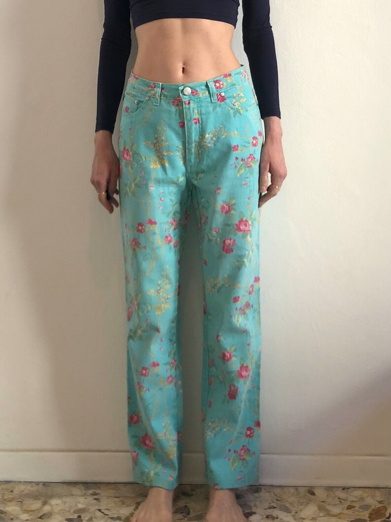 May include: A pair of light blue jeans with a floral print. The jeans have a straight leg and a high waist.
