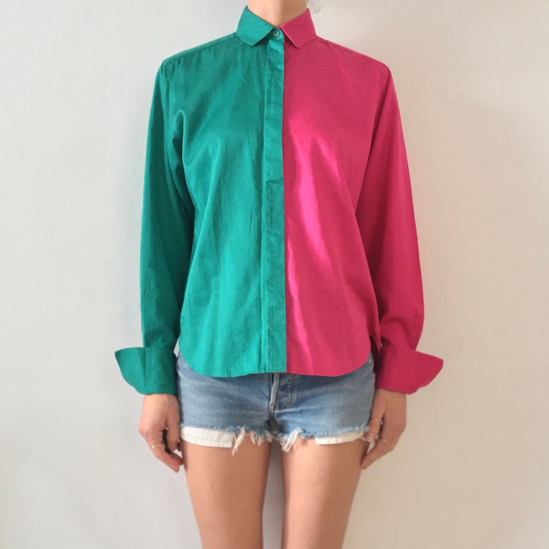 Puede incluir: Una camisa de manga larga con botones y un dise&ntilde;o de colores contrastantes. Una mitad de la camisa es verde azulado y la otra mitad es rosa intenso. La camisa tiene un cuello cl&aacute;sico y mangas largas con pu&ntilde;os abotonados.