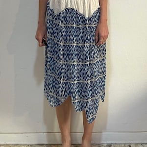 Op de afbeelding: Knie-lange rok met een witte tailleband en een blauw-wit patroon. De rok heeft een geschulpte rand en een vloeiend silhouet, ideaal voor een casual of bohemien look.