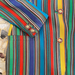 May include: A multi-colored striped blazer with gold buttons. The blazer has vertical stripes in shades of red, blue, green, yellow, and black.