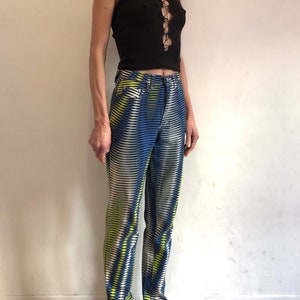 Puede incluir: Una camiseta negra sin mangas con un detalle de encaje en la parte delantera, combinada con pantalones de rayas azules y blancas con un patr&oacute;n geom&eacute;trico amarillo.