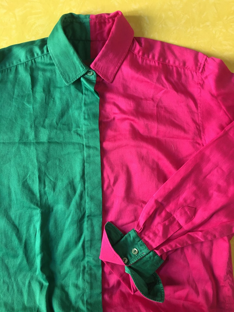 Puede incluir: Una camisa de manga larga con botones y un dise&ntilde;o de bloques de color verde y rosa. La camisa tiene cuello y cierre de botones.