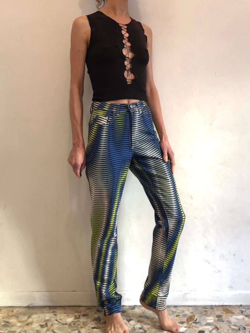 Puede incluir: Una camiseta negra sin mangas con un detalle de encaje en la parte delantera, combinada con pantalones de estampado azul y blanco.
