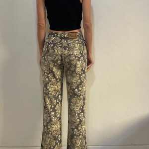 May include: A pair of brown floral print jeans with a brown leather patch on the back pocket that says "CJ".