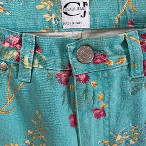 May include: A pair of blue denim jeans with a floral print. The jeans have a label that reads "Cavalli Jeans" and "Made in Italy".