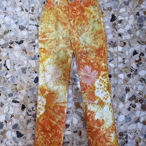 May include: Orange and yellow tie-dye jeans with a faded white pattern. The jeans have a high waist and a straight leg.