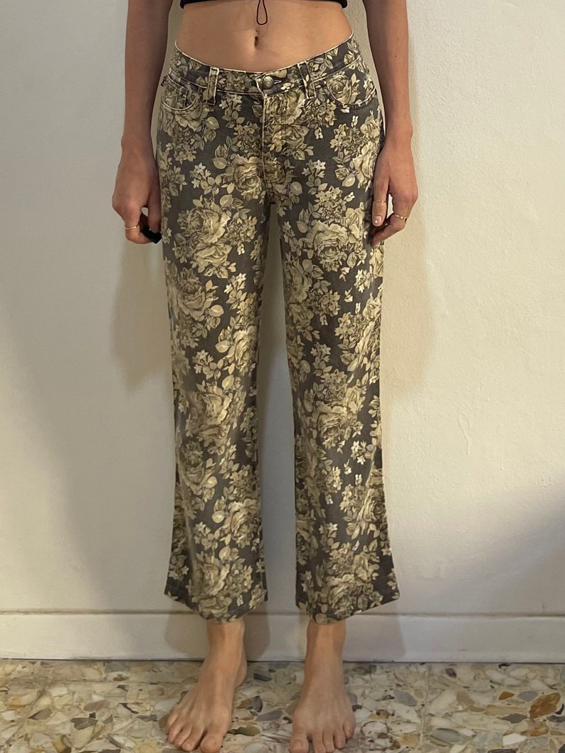 May include: A pair of wide-leg jeans with a floral print in shades of beige and brown.