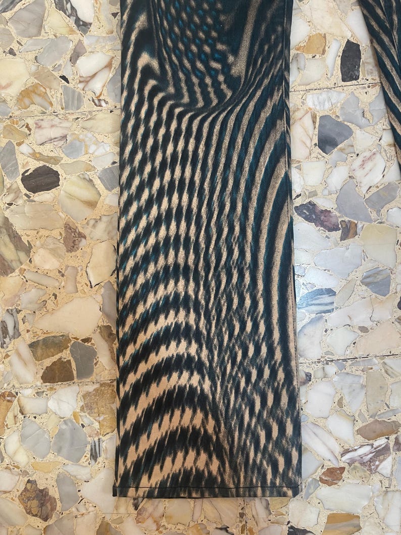 Puede incluir: Primer plano de la parte inferior de un pantal&oacute;n de patr&oacute;n negro y marr&oacute;n. El patr&oacute;n es un dise&ntilde;o abstracto en espiral.