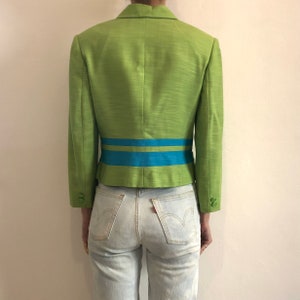 Pode incluir: Um blazer verde com uma faixa azul e verde na cintura.