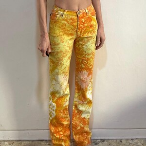 May include: A pair of yellow and orange tie-dye jeans with a high waist and a straight leg.