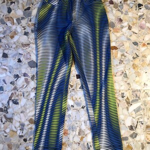 Puede incluir: Vaqueros con estampado azul, blanco y amarillo con la palabra "VERSACE" impresa en el bolsillo trasero.
